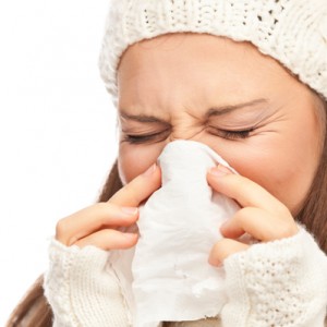 Girl in winter clothing sneezing